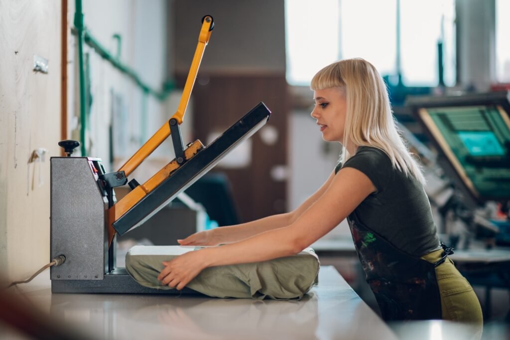 Print shop employee using heating press on screen printed t-shirt.