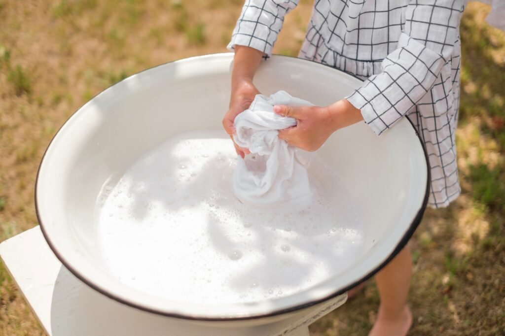 Close-up of children's hands washing a snow-white shirt in a basin.