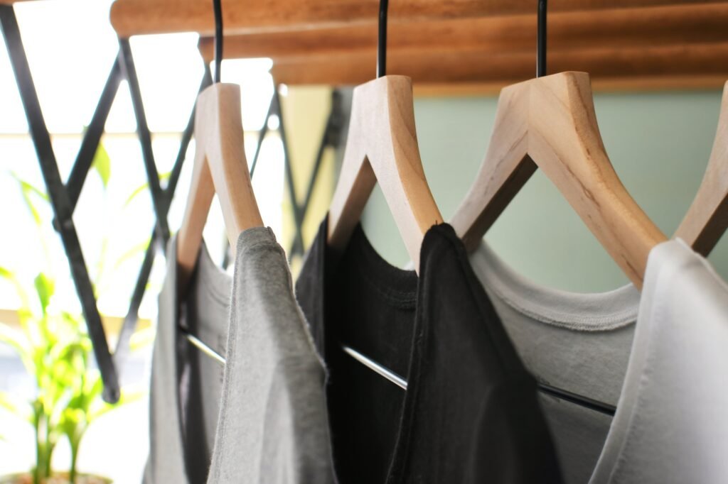 Simple basic t-shirts tee shirts hanging on wooden hangers in a laundry room on wash day.
